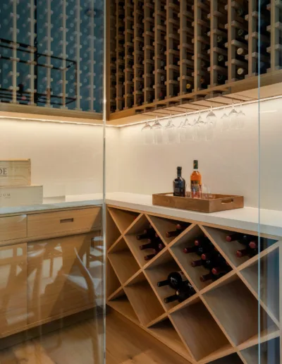 A wine cellar with wooden shelves and a glass door.