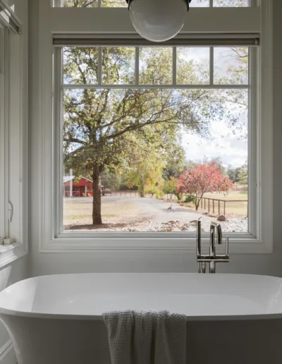 A bathroom with a large window overlooking a field.