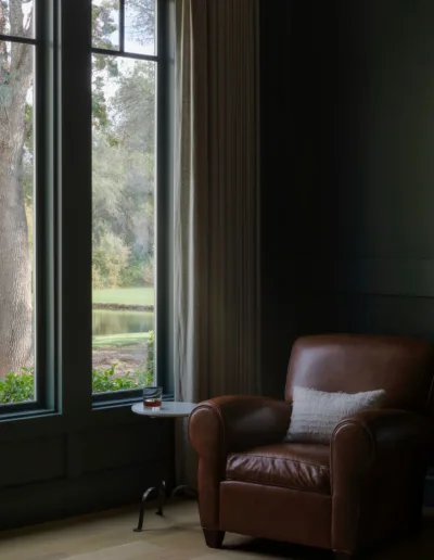 A brown leather chair in front of a window.