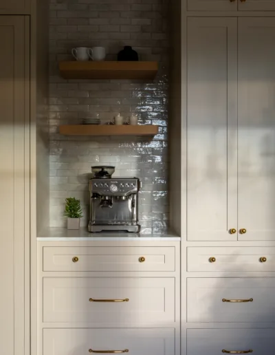 A kitchen with white cabinets and a coffee maker.