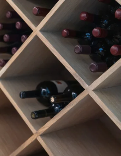 A wooden wine rack with a lot of bottles in it.