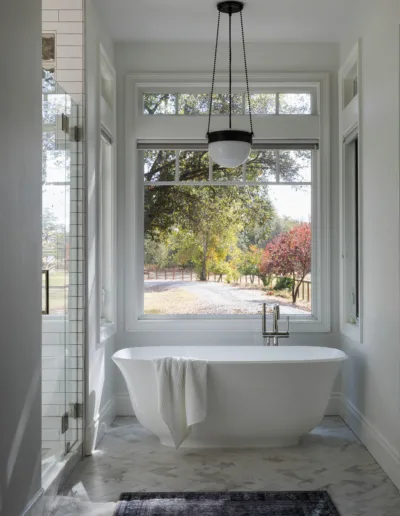 A white bathroom with large windows and a bathtub.