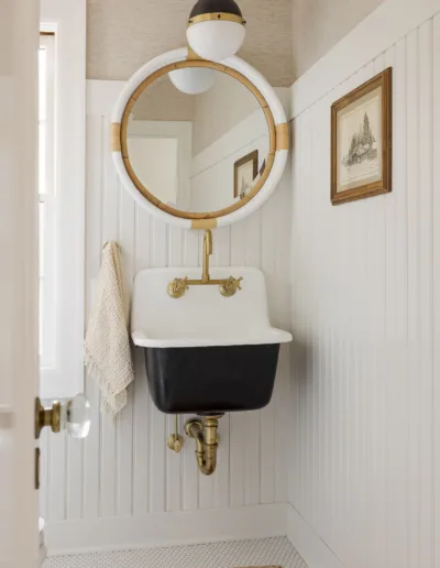 A bathroom with a white sink and an oval mirror.