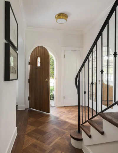 A hallway with a wooden door and black railing.