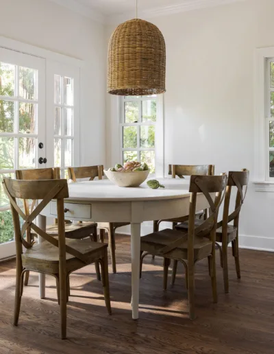 A white kitchen with wooden floors and a dining table.