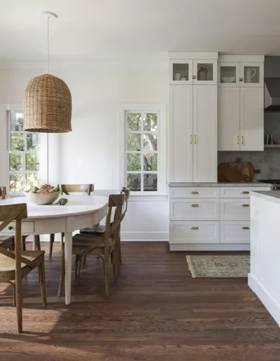 A white kitchen with wood floors and a dining table.
