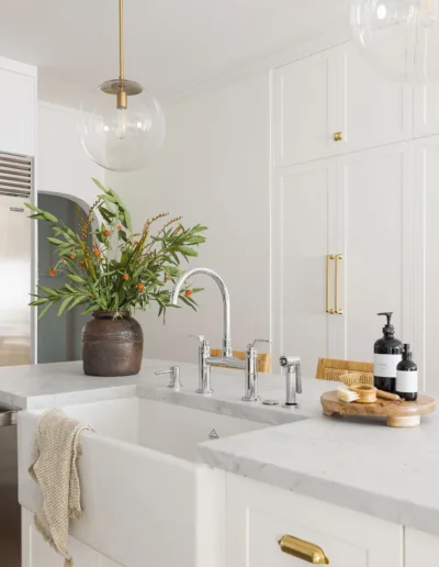A white kitchen with brass fixtures and a sink.