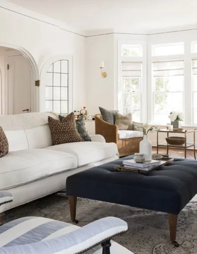 A living room with white furniture and a blue ottoman.
