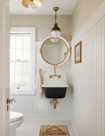 A white bathroom with a gold sink and mirror.