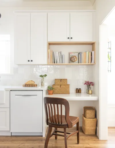 A white kitchen with a wooden chair and shelves.