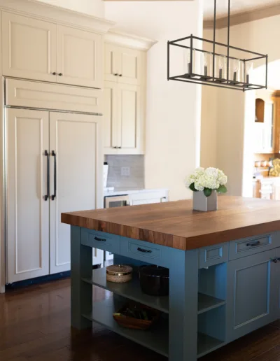 A kitchen with a blue island and white cabinets.