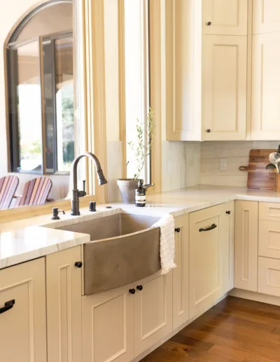 A kitchen with white cabinets and a wooden sink.