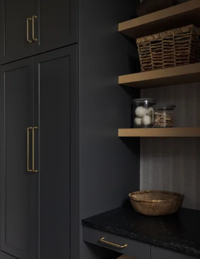 A laundry room with black cabinets and gold hardware.